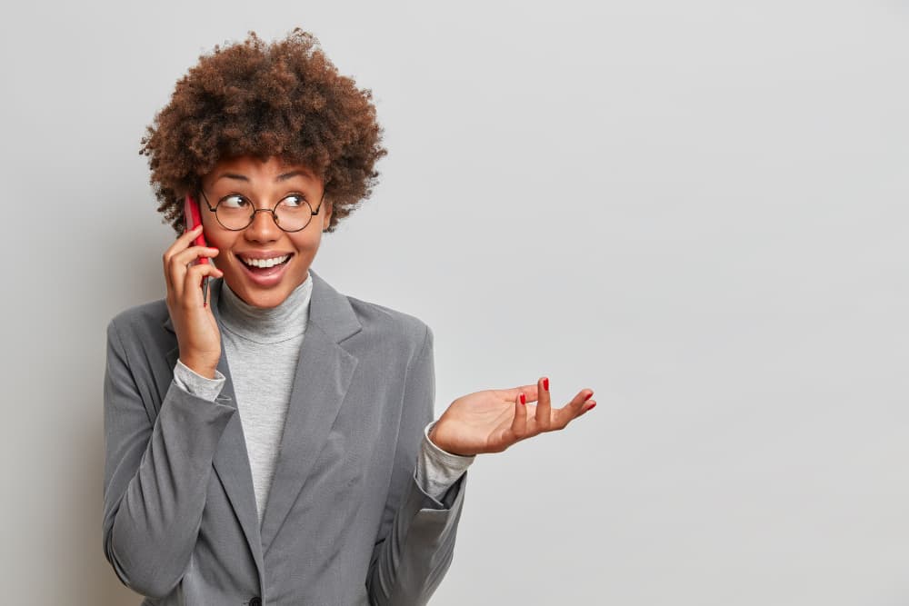 Smiling woman in a gray blazer taking a phone call